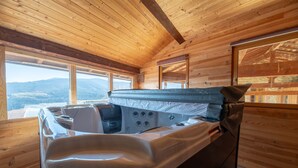 A wooden cabin interior with a hot tub, large windows, and a view of the mountains. - Eco-Lodge Cabin in Ardèche Close to Nature (Saint-Symphorien de Mahun)