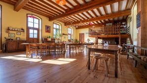 A spacious room with wooden floors, a high ceiling with exposed beams, a dining area with tables and chairs, and a loft with a balcony. - Eco-Lodge Cabin in Ardèche Close to Nature (Saint-Symphorien de Mahun)