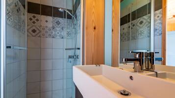 Une salle de bain avec une douche, un lavabo et un miroir.
