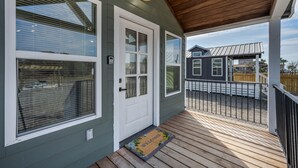 A wooden deck with a welcome mat, a white door, and a covered porch area. - Pet-Friendly Tiny Home Near Beach & Marinas (Rockport)