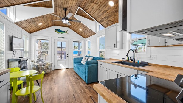 A modern kitchen with a wooden ceiling, a dining area with a yellow table and chairs, and a blue sofa. - Pet-Friendly Tiny Home Near Beach & Marinas (Rockport)