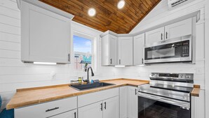 A modern kitchen with white cabinets, a wooden countertop, a stainless steel oven, and a microwave. - Pet-Friendly Tiny Home Near Beach & Marinas (Rockport)