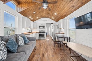 Una cocina amplia con techo de madera, armarios blancos y un comedor con mesa y sillas.