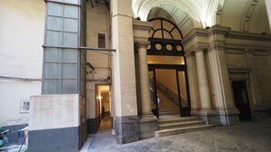 A grand entrance with a marble staircase leading to a second floor, flanked by large columns and a decorative archway. - Triple room 5 minutes from Castel dell'Ovo (Napoli)