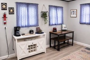 A room with a white cabinet, a coffee maker, a toaster, and a small table with a sign. - Sounds of the Waterfall - 1mi to Racetrack & Park (Montour Falls)
