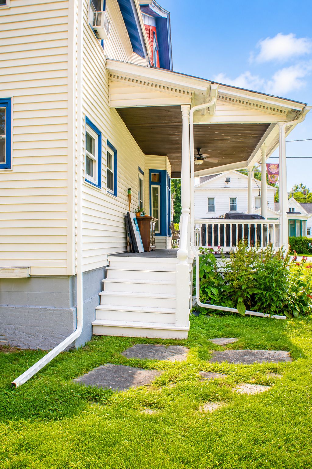 A two-story house with a covered porch, a front door, and a small front yard with stepping stones.