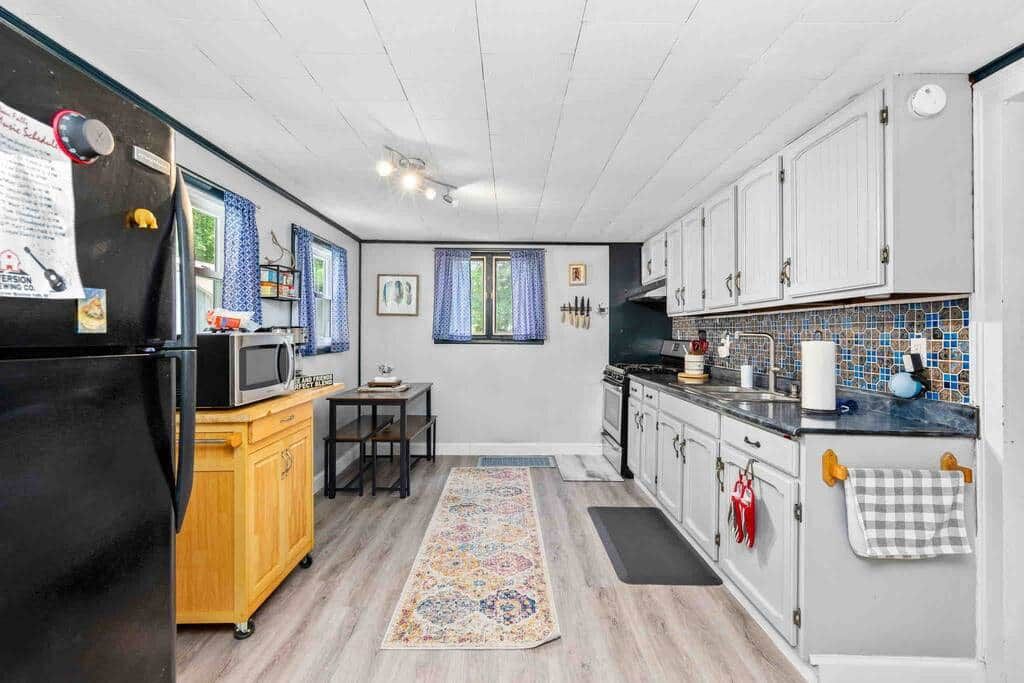 Une cuisine de taille réduite équipée d’un réfrigérateur, d’un four à micro-ondes et d’un meuble en bois.