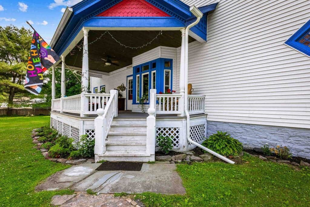 Una casa con portico, scalini e un piccolo giardino.