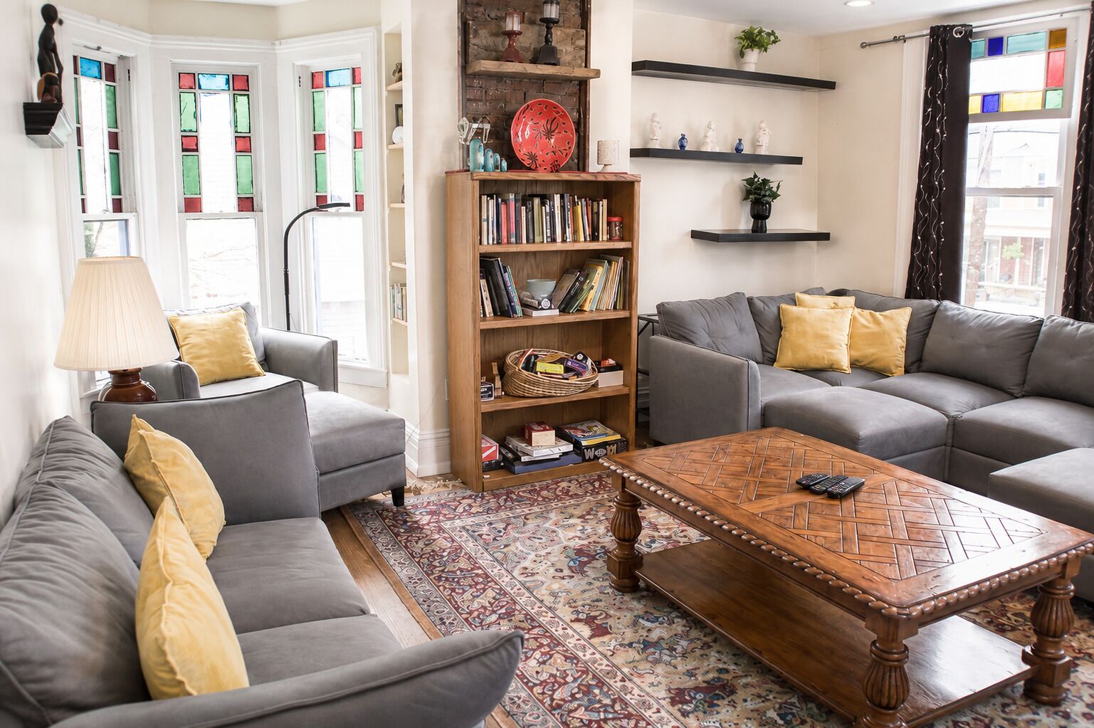 A living room with two grey sofas, a wooden coffee table, a bookshelf, and a patterned rug.