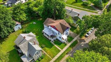 An aerial view of a residential area with a large house featuring a prominent gable roof and a smaller attached structure.