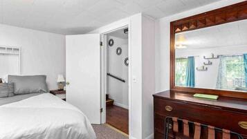 Une chambre à coucher comprenant un lit, une commode, un miroir et une porte donnant sur un escalier.