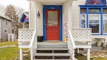 A house with a red door, a welcome sign, and a blue window.