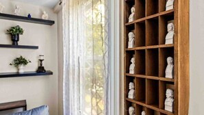 Ein Zimmer mit großem Fenster, Regalen mit Dekoration und einer Hollauslage mit Büsten.