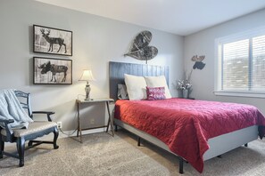 Une chambre à coucher comprenant un lit, une chaise, une table de chevet et des œuvres d’art murales.