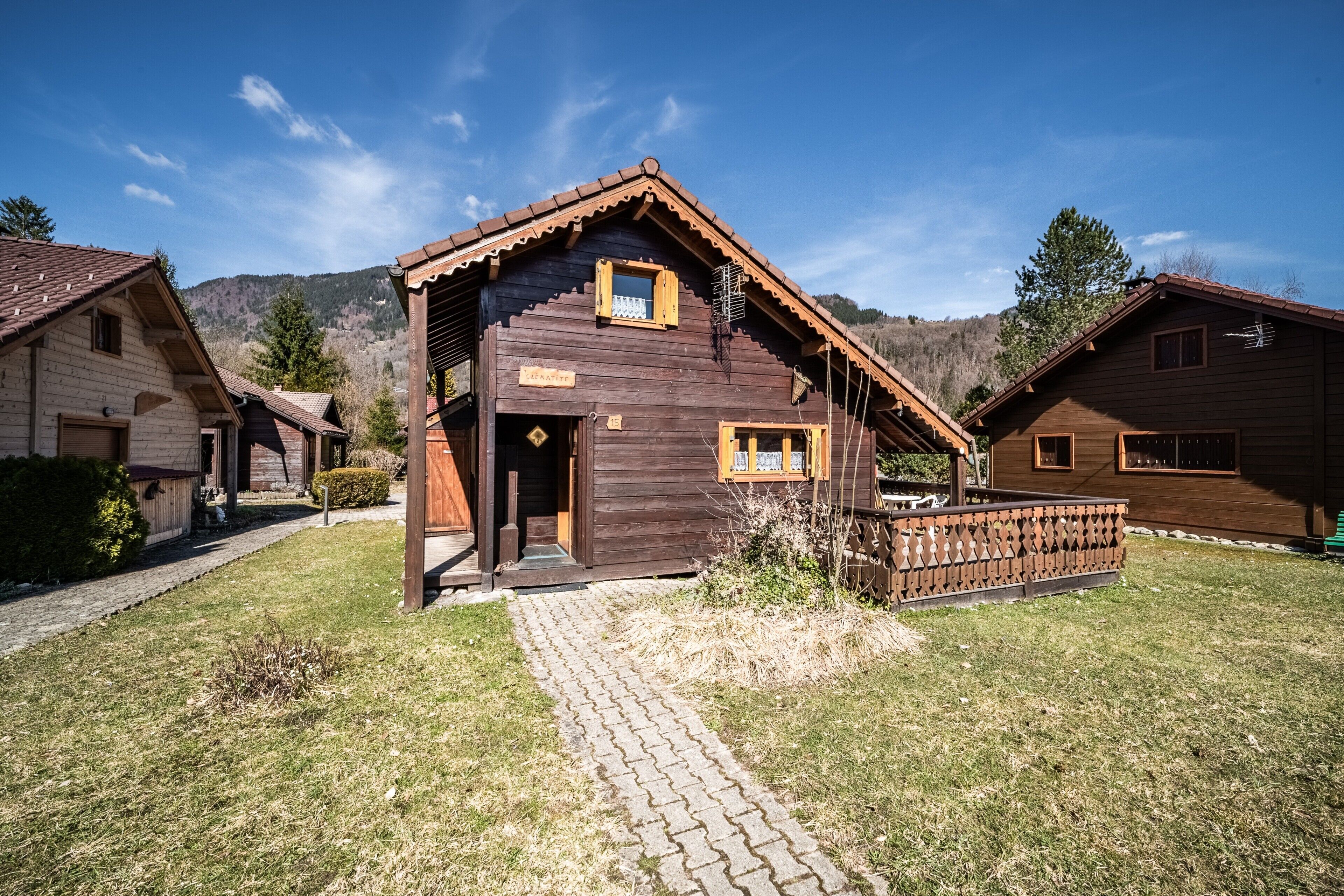 A wooden cabin with a porch, a brick pathway, and a mountain backdrop.