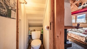 Een houten interieur met een toilet, een bed en een raam met uitzicht.