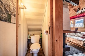 A wooden interior with a toilet, a bed, and a window with a view. - Chalet “6p Classique - Clématite” with Mountain View, Private Terrace & Wi-Fi (Verchaix)