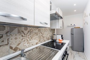 A modern kitchen with a stainless steel sink, a built-in stove, and a refrigerator. - Toto House - Historic Center (Catania)