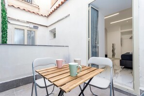 A wooden table with two chairs, two mugs, and a view of a living area with a sofa and a vase. - Toto House - Historic Center (Catania)