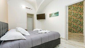 Un dormitorio con cama, televisor de pantalla plana, un cuadro y una puerta con estampado floral.