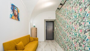 Un pasillo con un sofá amarillo, un papel tapiz floral y una puerta.
