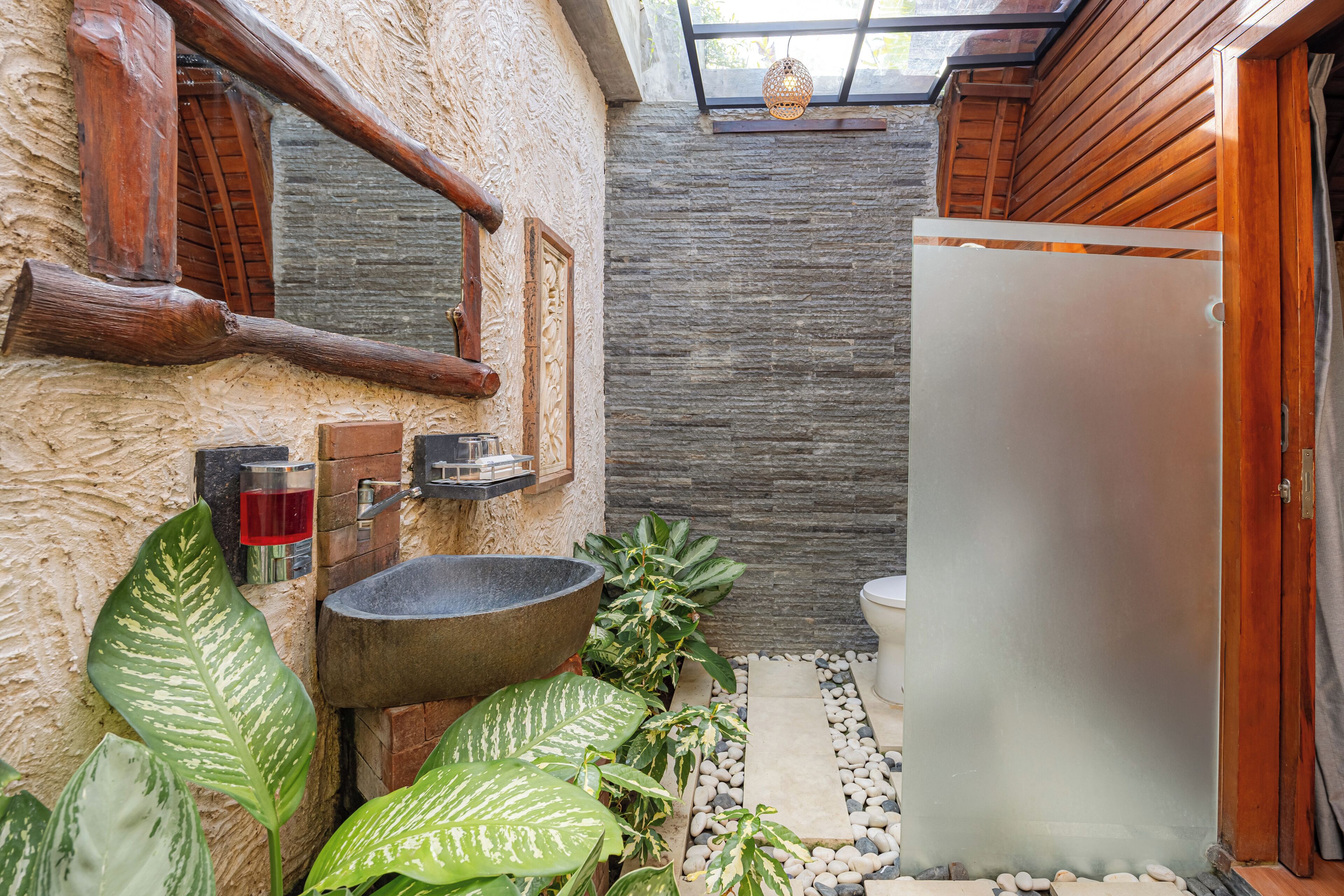 A bathroom with a stone sink, wooden window frame, and a toilet.
