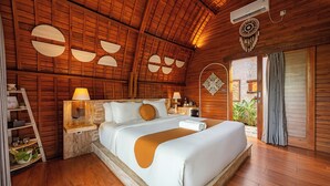 Une pièce en bois avec un grand lit, des murs en bois et un ventilateur de plafond.