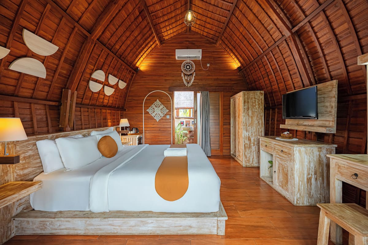 Une pièce spacieuse avec un grand lit, des murs en bois, une télévision et une petite kitchenette.