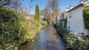 A narrow waterway flanked by lush greenery and traditional buildings. - Gatehouse Cottage, Cartmel (Cartmel)
