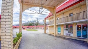Un motel doté d’un parking couvert, d’une façade en briques et d’une structure à plusieurs étages avec des balcons.