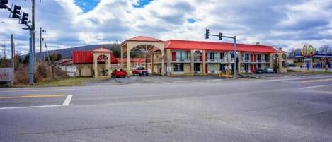 Un motel avec un toit rouge et, au fond, une enseigne McDonald's.
