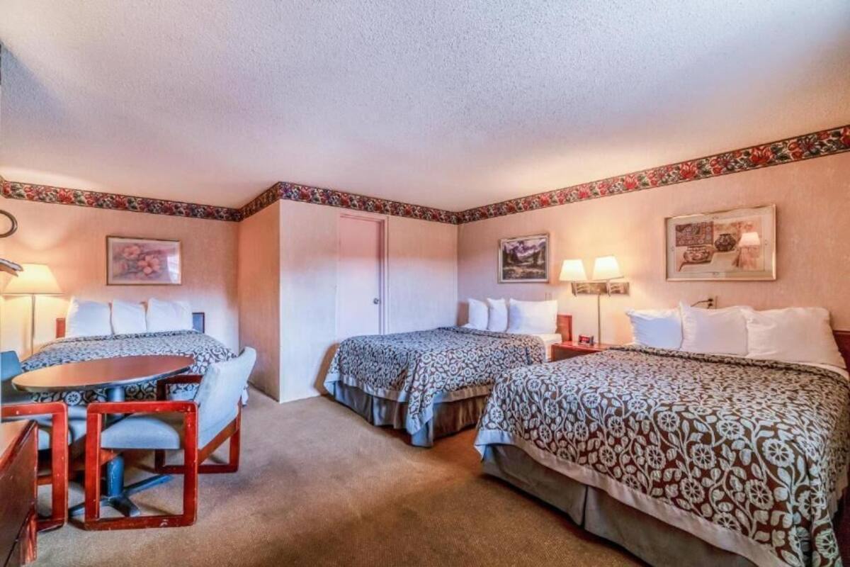 A hotel room with two beds, a small table, and a chair.