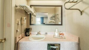 Une salle de bain équipée d’un lavabo, d’un miroir, d’un porte-serviettes et d’un sèche-mains.