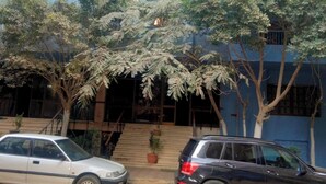 A building with a blue exterior, two cars parked in front, and a staircase leading to the entrance. - Star House: Steps to Grand Egyptian Museum (Giza Governorate)