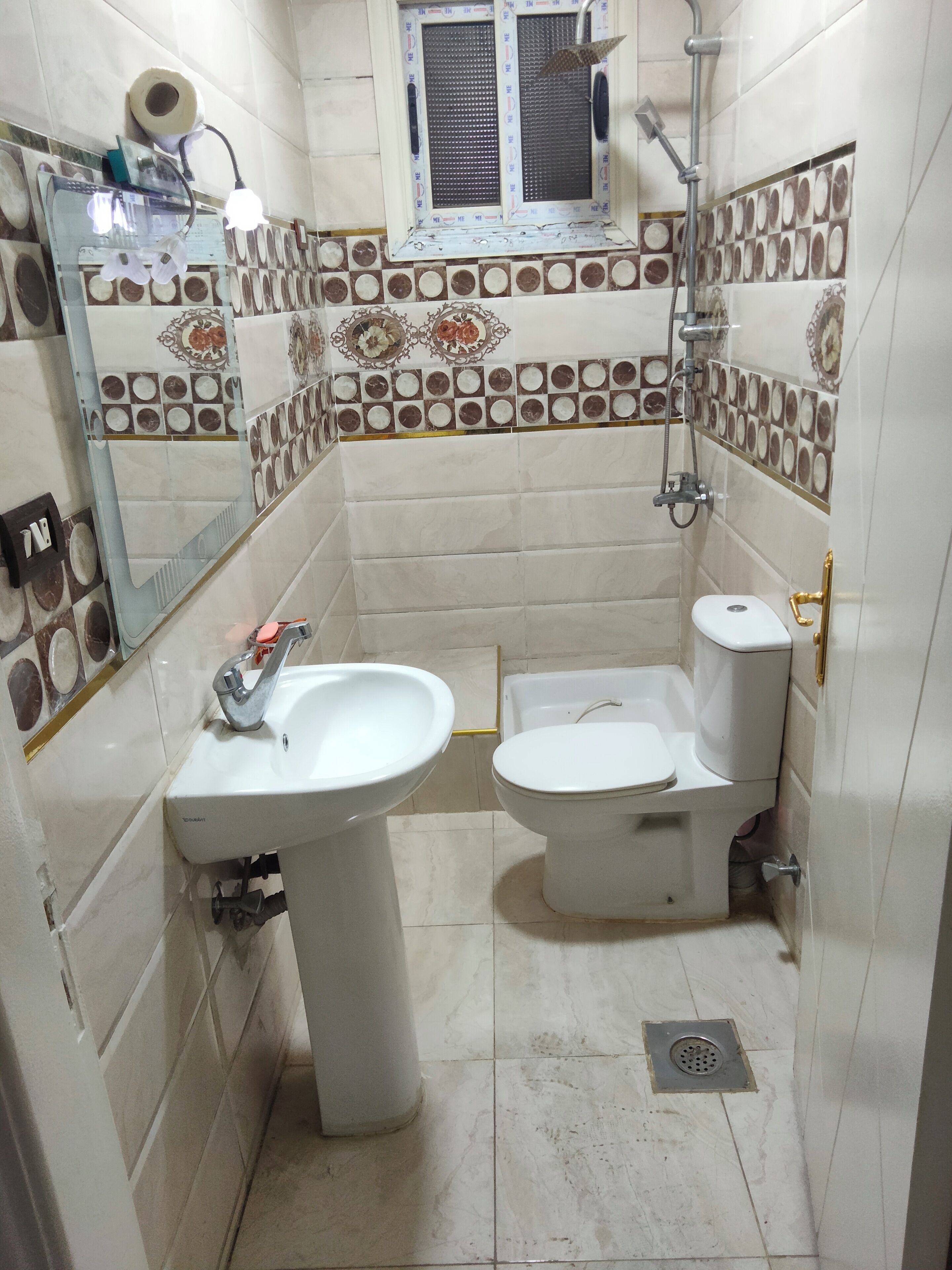 Une salle de bain équipée d’un lavabo, de toilettes, d’une douche et de carreaux décoratifs.