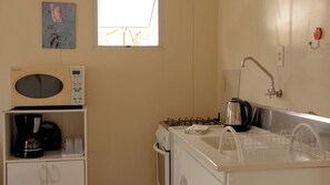 A compact kitchenette with a microwave, coffee maker, gas stove, and sink. - Pousada Recanto Bella Rosa (Imbituba)