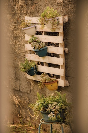 A vertical wooden structure with multiple planters against a textured wall. - Pousada Recanto Bella Rosa (Imbituba)