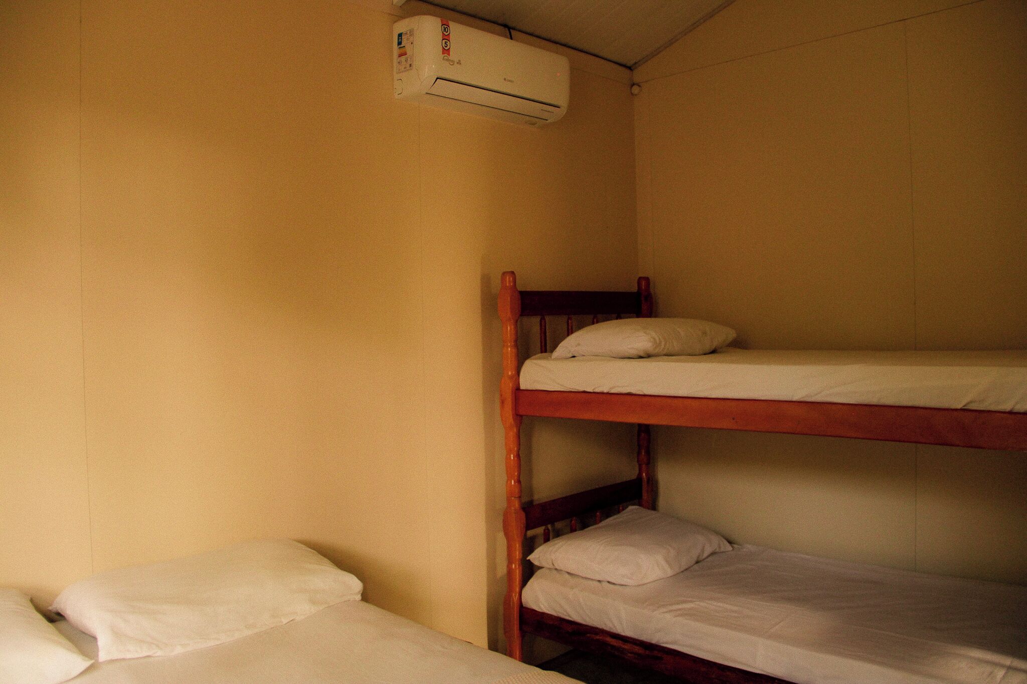 Et soveværelse med køjesenge og en enkelt aircondition installeret på væggen.