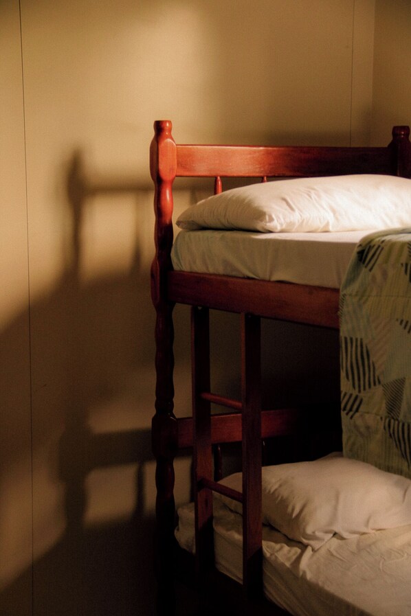 A bunk bed with a wooden frame and white bedding. - Pousada Recanto Bella Rosa (Imbituba)