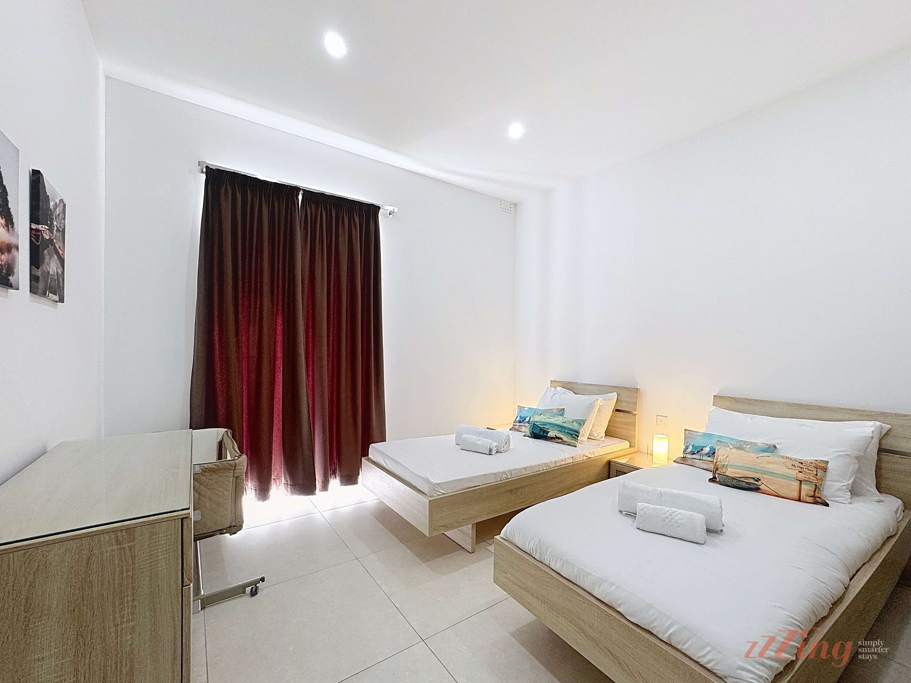 Ein Hotelzimmer mit zwei Betten, einem Schreibtisch und einem Fenster mit Vorhängen.