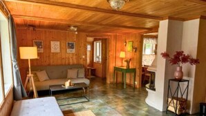 Un interior de madera acogedor con sofá, mesa de centro y zona de comedor.