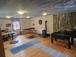 A room with a dartboard, a fireplace, a pool table, and a desk with a laptop.