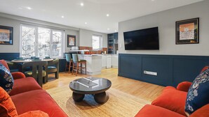 Un salon moderne comprenant un coin repas, une cuisine et un téléviseur fixé au mur.
