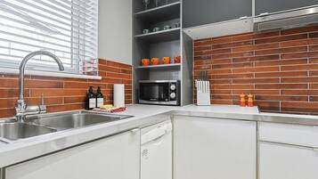 A modern kitchen with a stainless steel sink, a microwave, and a dish rack.