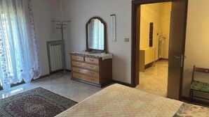 Ein Schlafzimmer mit einem Bett, einem Schminktisch, einem Spiegel, einer Heizung und einer Tür zu einem Badezimmer.