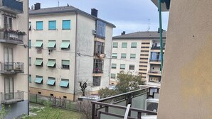 Ein Wohngebäude mit mehreren Balkonen, einem befestigten Eingangsbereich und Blick auf eine Grünfläche.
