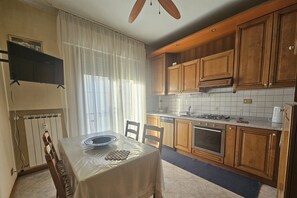 A kitchen with wooden cabinets, a gas stove, and a tiled backsplash. - Cozy and away from traffic, just 3 minutes from the bus stop (Venezia)