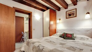 A bedroom with a bed, wooden door, and a painting on the wall. - Leo Apartment (Venezia)