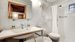 A bathroom with a marble sink, a wooden vanity, a toilet, and a shower with a glass door. - Leo Apartment (Venezia)