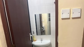 Un baño con lavamanos, inodoro y espejo blancos.